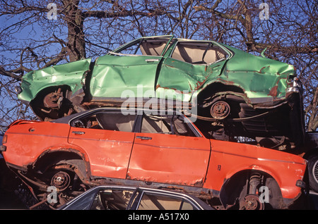 Vecchio fracassato automobili fino ad alta impilati nel cantiere di interruttori Foto Stock