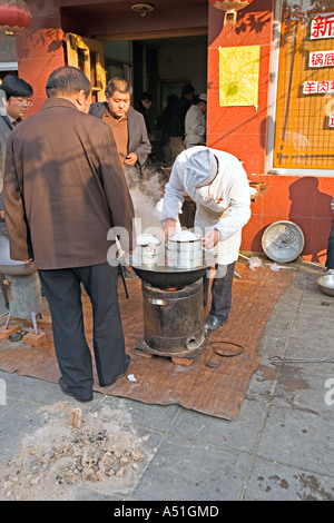 Cina Pechino minuscolo ma occupato quartiere ristorante con chef impostato sul marciapiede per preparare la colazione gnocchi Foto Stock