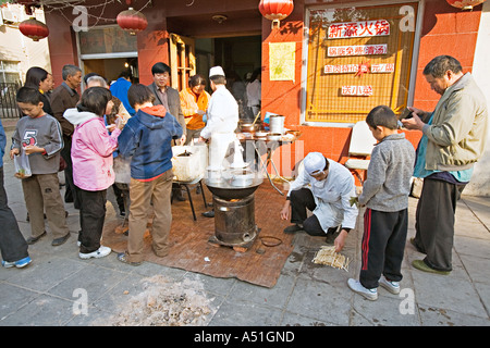 Cina Pechino minuscolo ma occupato quartiere ristorante con chef impostato sul marciapiede per preparare la colazione gnocchi Foto Stock