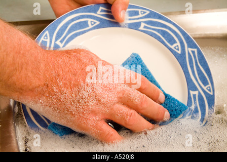 Uomo che lava i piatti a mano Foto Stock