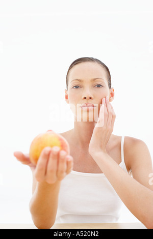 Una giovane donna che mantiene una pesca guardando la fotocamera Foto Stock