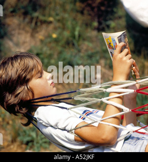 Fumetto adolescente di lettura rilassante all'aperto in amaca. Foto di Willy Matheisl Foto Stock