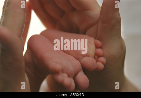 Madre teneramente contiene piccoli piedini del suo 6 giorni baby Russia Foto Stock