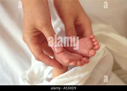 Madre teneramente contiene piccoli piedini del suo bambino la Russia Foto Stock