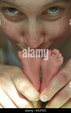 Madre teneramente trattiene e baci piccoli piedini del suo 6 giorni baby Russia Foto Stock