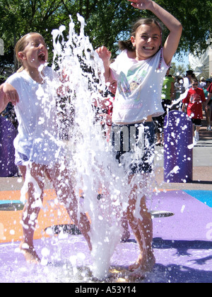 2 ragazze divertirsi e bagnarsi in una fontana di acqua Foto Stock