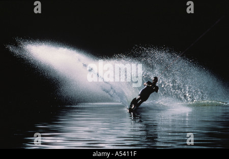 Spray bianco da sci d'acqua contro dark riverbank sul fiume Hawksberry in Australia Foto Stock