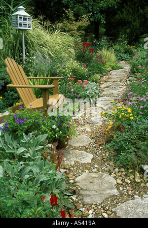 Giardino di Roccia curve del percorso attraverso il giardino fiorito con sedia Adirondack e birdhouse, STATI UNITI D'AMERICA Foto Stock