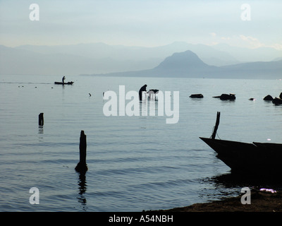 Ip Painet1684 guatemala donna lavando vestiti lago Atitlan san pedro uomo pagaie passato canoa paese nazione in via di sviluppo meno Foto Stock
