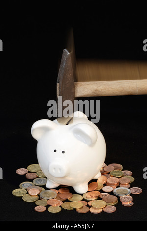 Un martello cade sulla banca apiggy con le monete in euro Foto Stock