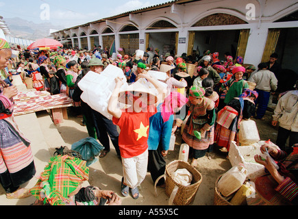 Un ragazzo vietnamita trasporta i contenitori in plastica utilizzati nella vendita di liquore casalingo al mercato di BacHa Vietnam del Nord Foto Stock