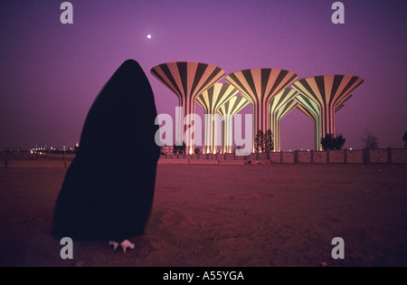 Donna musulmana orologi moon over acqua Kuwait Towers di notte Foto Stock