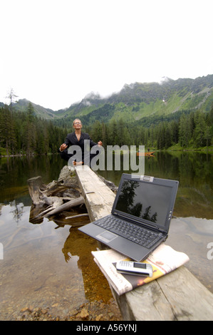 Imprenditrice meditando sul lago con il computer portatile in primo piano Foto Stock