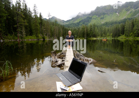 Imprenditrice seduti in riva al lago di laptop in primo piano Foto Stock