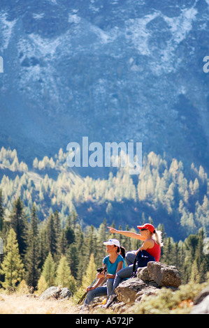 Due donne sedute su roccia in montagna, vista laterale Foto Stock