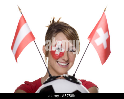 Giovane donna con bandiera svizzera dipinto sul volto e tenendo il calcio con bandiera Foto Stock