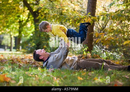 Padre giacente in prato, figlio di sollevamento Foto Stock