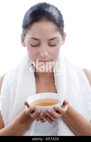 Giovane donna azienda tazza di tè a occhi chiusi, close-up Foto Stock