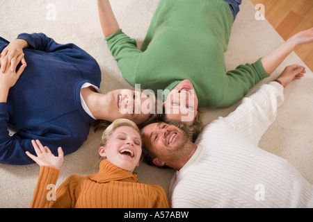 Famiglia sdraiato sul pavimento nel soggiorno, vista in elevazione Foto Stock