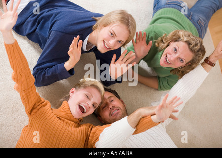 Famiglia sdraiato sul pavimento nel soggiorno, sorridente, vista in elevazione Foto Stock