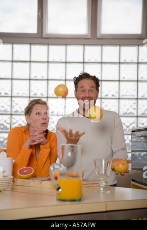 Coppia matura in cucina, uomo giocoleria con pompelmi Foto Stock