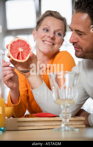 Coppia matura mangiare pompelmo in cucina, Donna sorridente Foto Stock