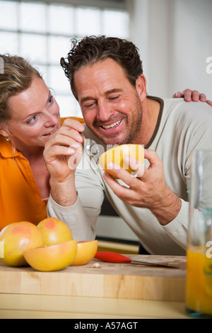 Coppia matura mangiare pompelmo in cucina, sorridente, close-up Foto Stock