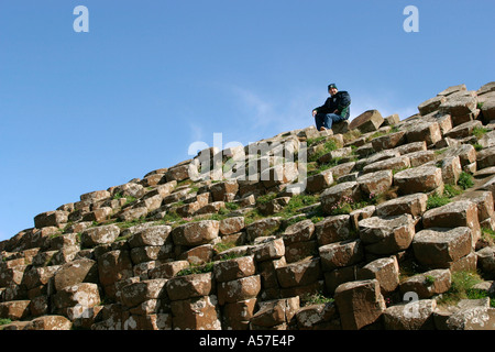 Contea di Antrim Giants Causeway uomo seduto sulle rocce Foto Stock