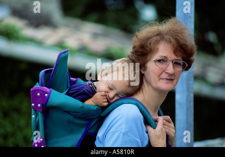 La nonna che porta il suo nipote del sonno in uno zaino. Foto Stock