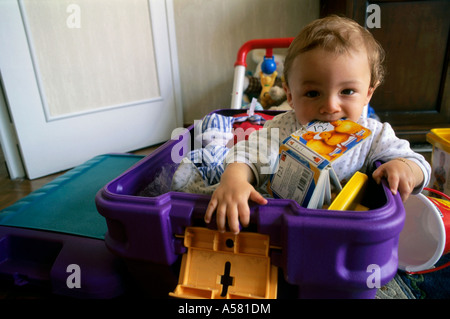 Un anno di età bambino giocando nella sua scatola di giocattoli. Foto Stock