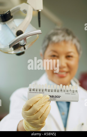 Senior femminile asiatica dentista dente di trattenimento dei campioni di colore Foto Stock