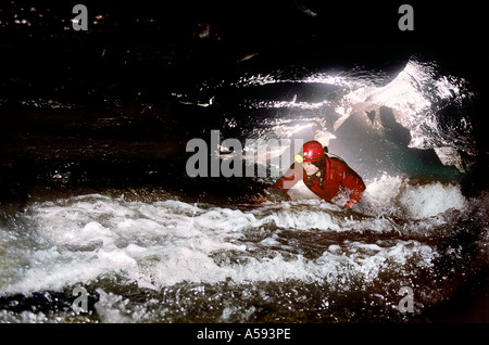 Femmina speleologo strisciando nel Galles del Sud grotta streamway REGNO UNITO Foto Stock