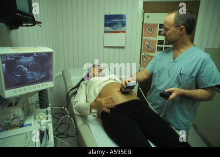 Medico di eseguire test ad ultrasuoni sulla donna asiatica con feto sullo schermo Foto Stock