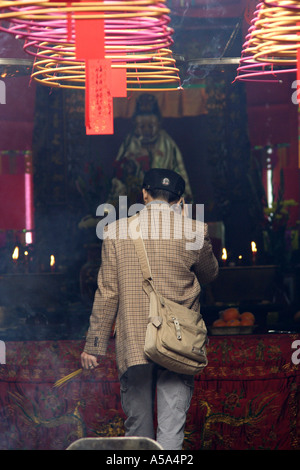 Di Hong Kong, Kowloon, il Tempio di Tin Hau, uomo sul suo telefono cellulare ad offrire incenso, Cina Foto Stock