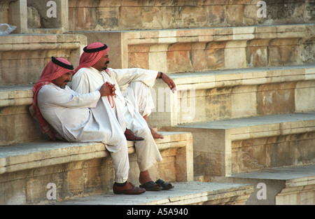 Due uomini palestinese seduti sui gradini del teatro romano di Amman, Giordania Foto Stock