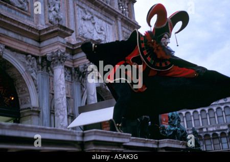 Un uomo che indossa una maschera e costume di fantasia finge di volare durante il carnevale veneziano a Venezia Italia Foto Stock