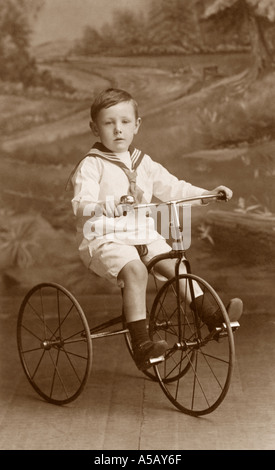 Originale ritratto in studio dell'era WW1 di un ragazzo che indossa un costume da marinaio che cavalca il suo triciclo giocattolo, Rochdale, Greater Manchester, Regno Unito, circa 1914 Foto Stock