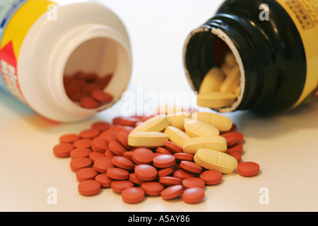 Colorato Generico Compresse di vitamina fuoriuscita da due bottiglie di medicina su sfondo bianco Foto Stock