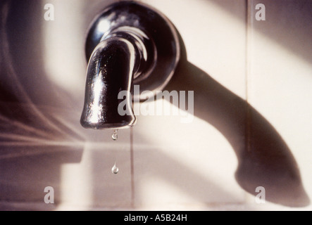 Rubinetto dell'acqua con due gocce d'acqua che gocciolano dal rubinetto nel lavandino. Gocce d'acqua o goccioline. Interni residenziali Foto Stock