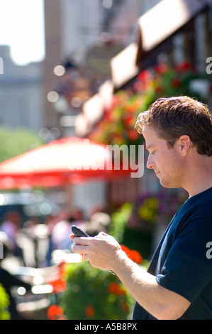 Uomo che utilizza blackberry cellulare un dispositivo PDA su posizione nella parte anteriore del summer street cafe. Foto Stock