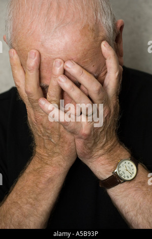 Emotional vecchio uomo che ricopre la faccia con le mani nella disperazione. Foto Stock