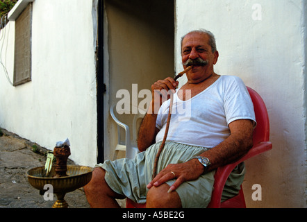 Uomo senior di fumare narghilè davanti la casa, Beirut, Libano Foto Stock