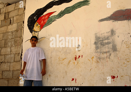 Ragazzo in piedi contro il muro con graffiti, Shatila Refugee Camp, Beirut, Libano Foto Stock