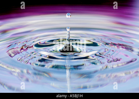 Acqua colorata goccia e ripple. Acqua su una piastra con specchio riflette il colore dello sfondo. Foto Stock