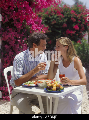 Coppia giovane bere e mangiare al fresco sulla terrazza con fiori di bouganville in background Foto Stock