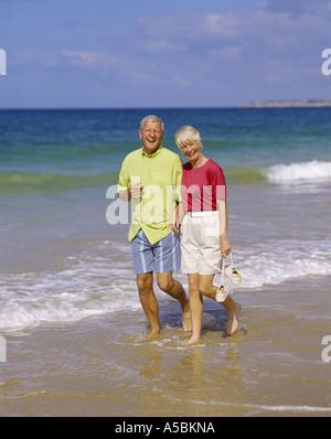 Coppia in pensione camminando sulla spiaggia Foto Stock
