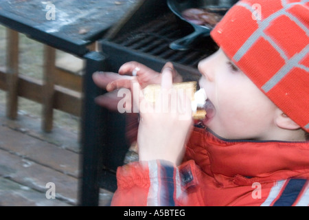 Età bambino 6 mangiare un smore realizzato da squishing riscaldata marshmallow e cioccolato tra graham cracker. Clitherall Minnesota USA Foto Stock