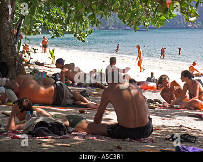 I villeggianti riparo sotto albero dal feroce sole di mezzogiorno Ao Nang Beach vicino a Krabi Thailandia Foto Stock