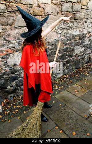 Una bambina vestita come una strega con una scopa in piedi su un sfondo di  parete viola Foto stock - Alamy