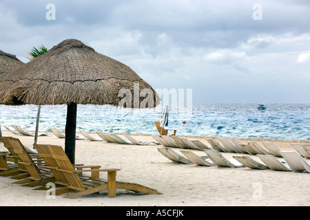 Spiaggia sabbiosa a Cozumel, Messico con il tetto di paglia con ombrelloni e sdraio in spiaggia per i turisti Foto Stock